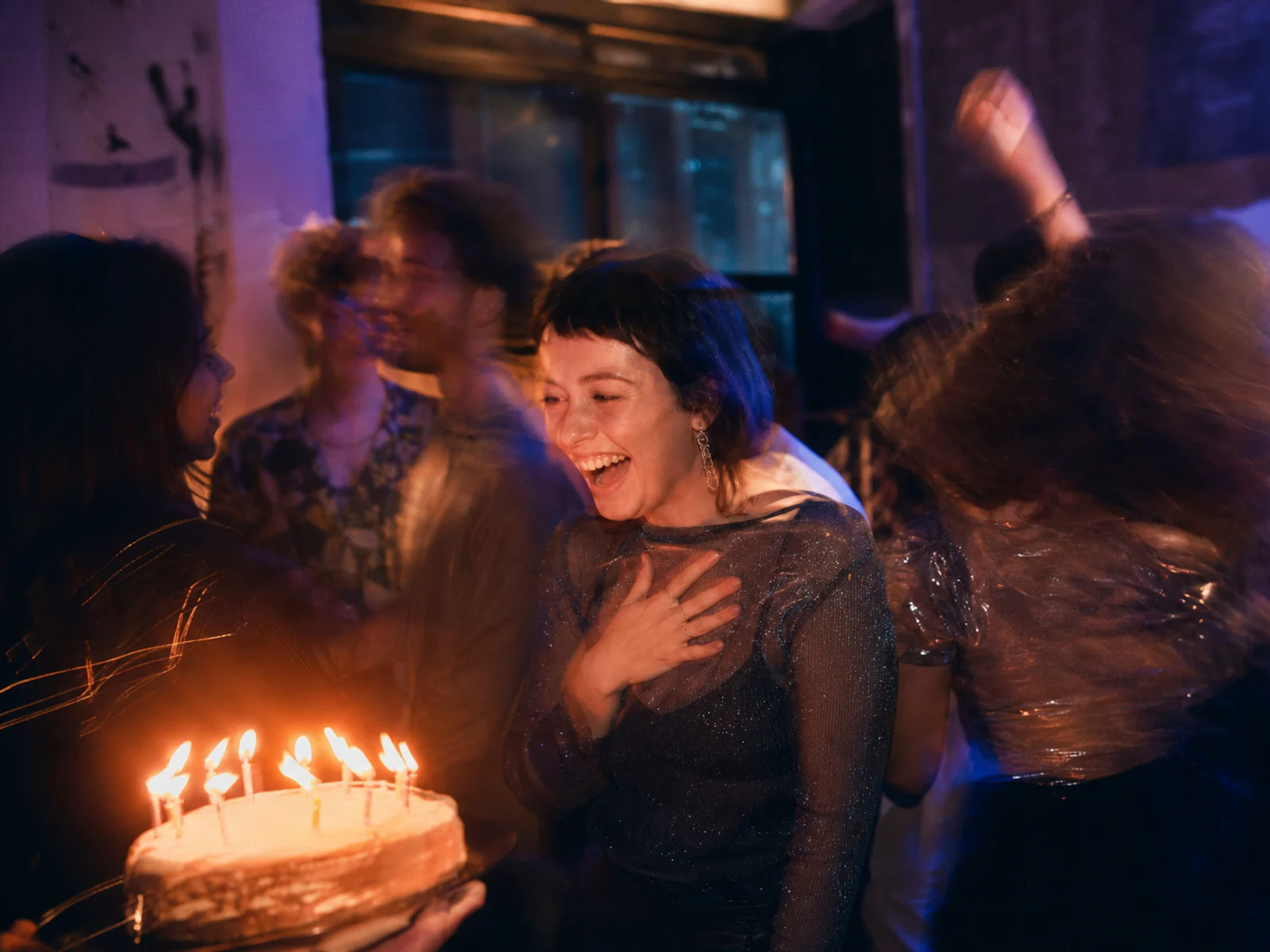 Slow-shutter birthday dance floor beside a glowing cake