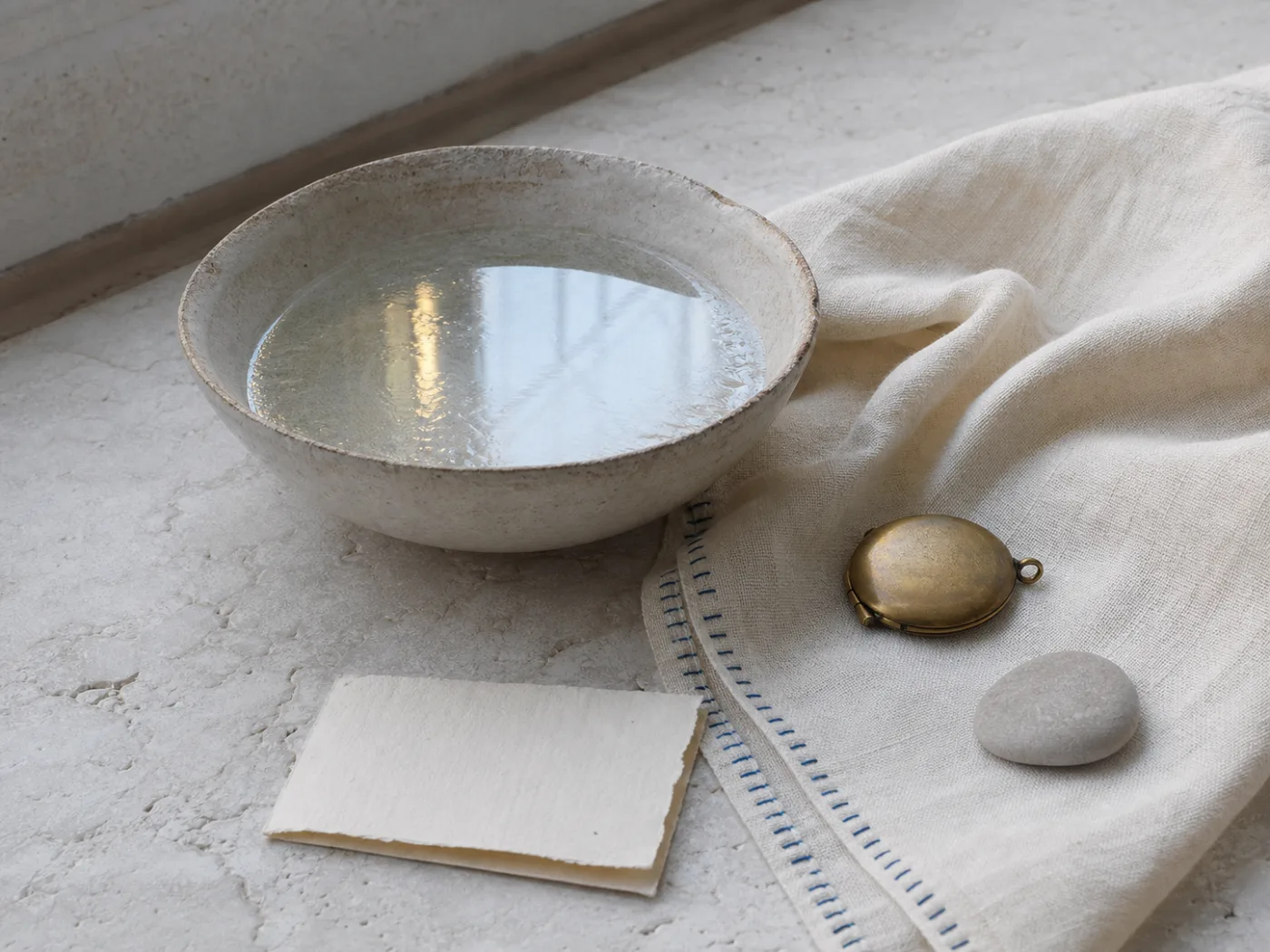 Still life of water, linen, and inherited family objects arranged with restraint