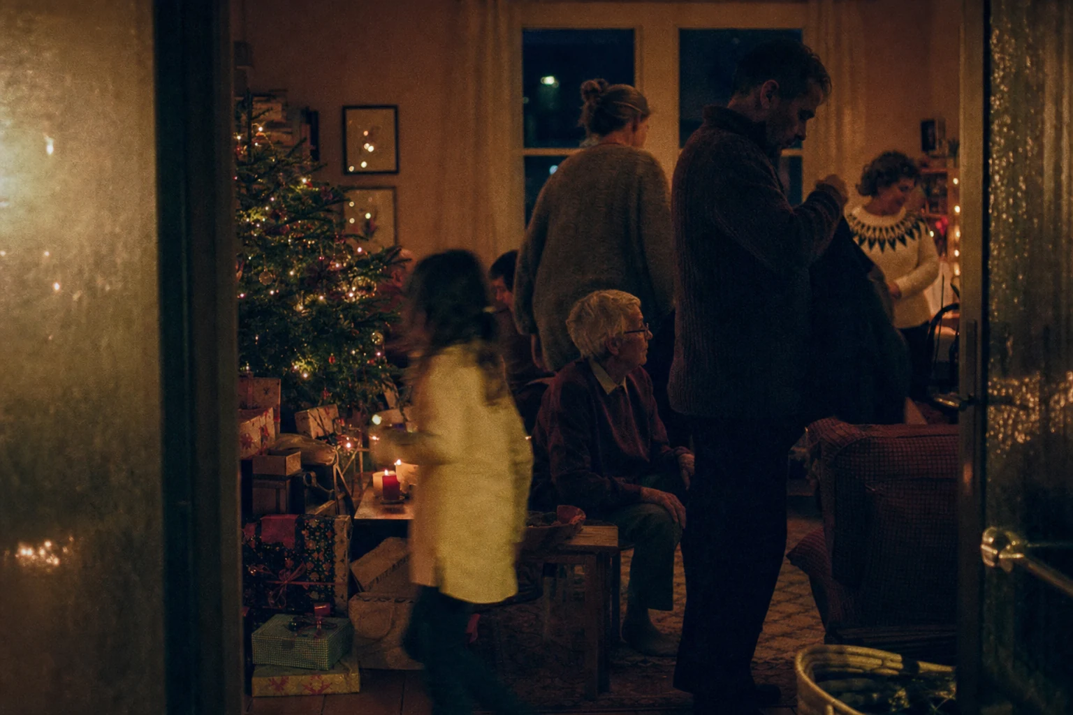 Grainy winter-night family scene in deep red, midnight blue, and candle gold