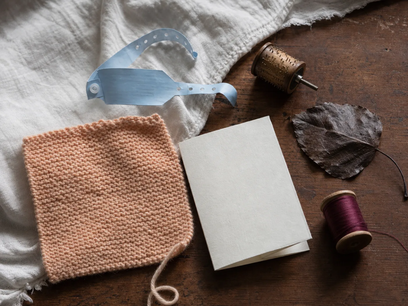 Tactile still life of a hospital bracelet, knitted blanket, and handwritten arrival card