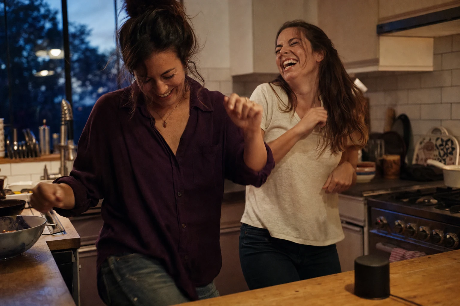 Two adult sisters dancing while hearing a personalized song in a kitchen